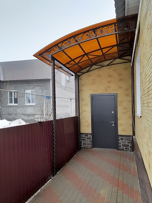 Односкатный навес с поликарбонатом в виде пристройки к дому с декоративной ковкой